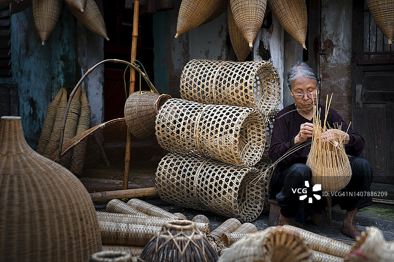 越南，守士村，清晨做渔具编织的越南老年妇女图片素材