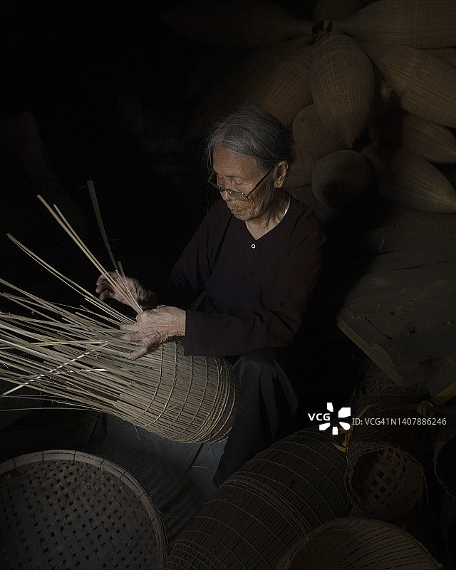 越南，守士村，清晨做渔具编织的越南老年妇女图片素材