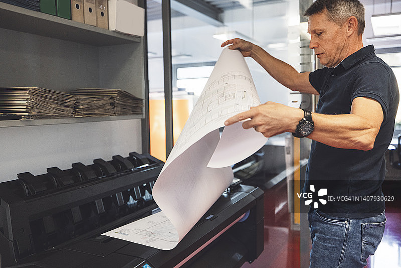 从打印机中取出蓝图的建筑师图片素材