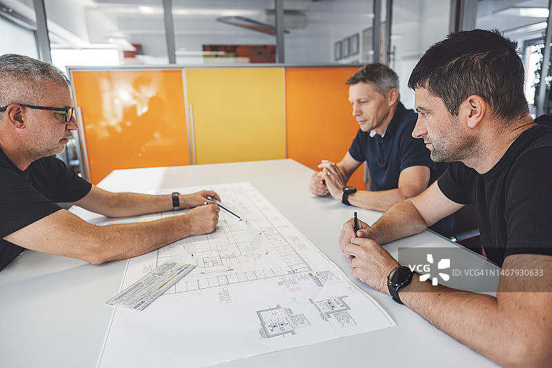 三名白人建筑师正在开会，看着蓝图图片素材