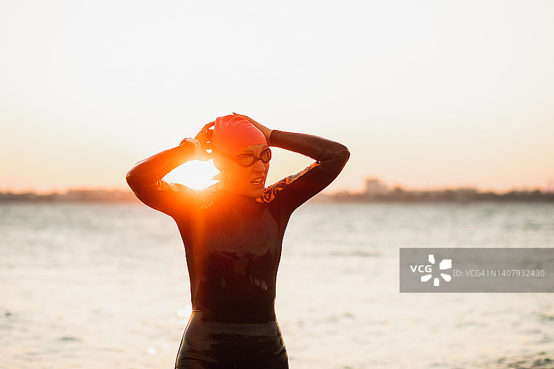 疲惫的女运动员在开放水域训练后佩戴游泳镜参加铁人三项比赛图片素材