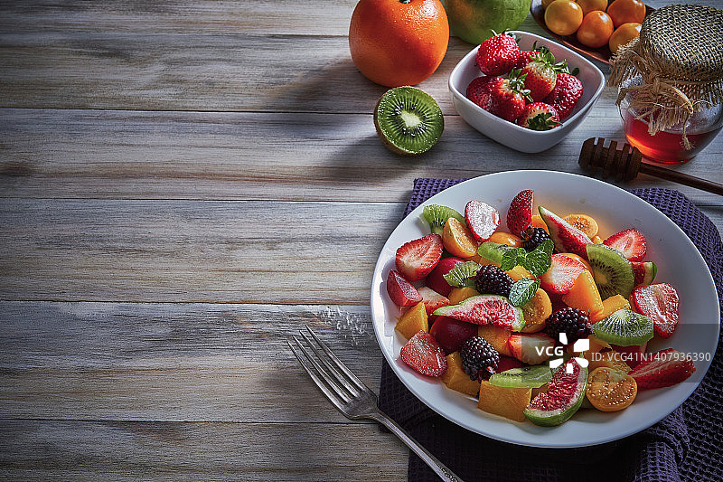 纯素食品主题。乡村木桌上新鲜的多种颜色热带水果碗特写顶部视图，带有复制空间图片素材