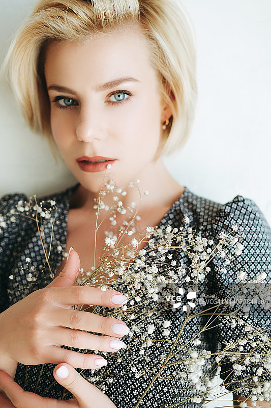 拥抱白色花苞植物的年轻女人图片素材