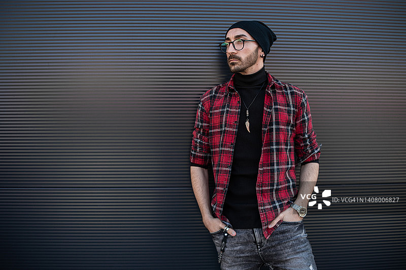 靠在灰色墙壁上的年轻潮男图片素材