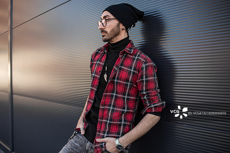 靠在灰色墙壁上的年轻潮男图片素材