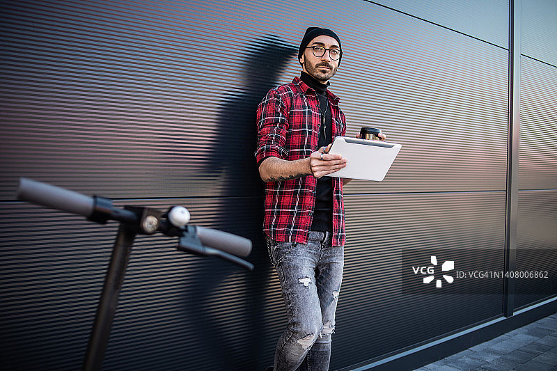 倚靠在灰色墙壁上的时尚年轻人，都市生活方式图片素材