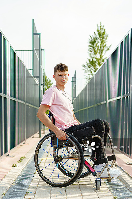 坐在篮球场上的残疾青年男子竖版全身照图片素材