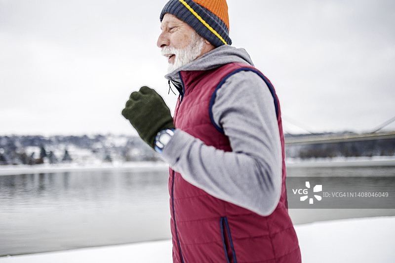 穿着冬装的中年跑步者在河边慢跑图片素材