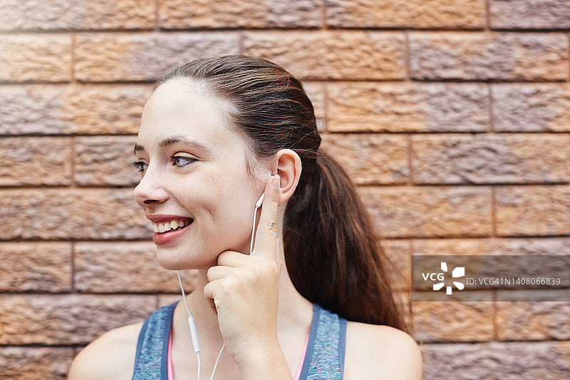 年轻女子戴耳机听音乐，面带笑容图片素材