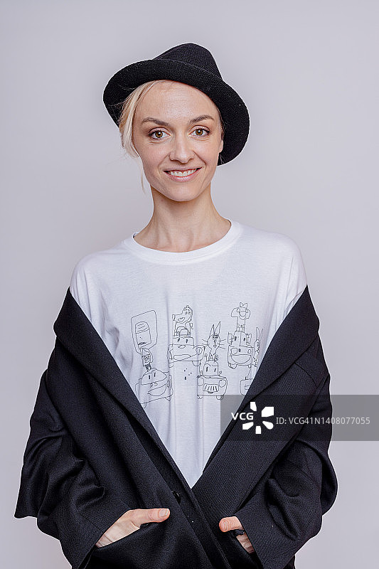 戴着猪肉馅饼帽在灰色背景工作室摆姿势的微笑女人图片素材