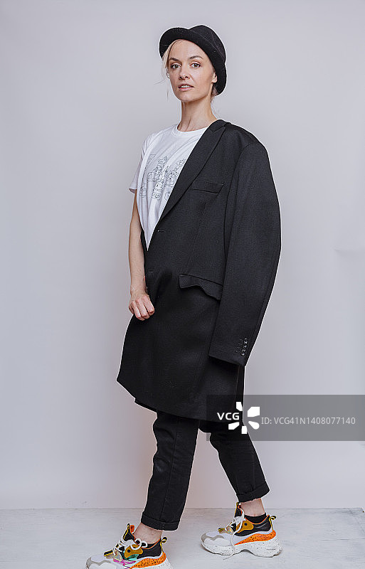 戴着猪肉馅饼帽在灰色背景工作室摆姿势的时尚女人图片素材