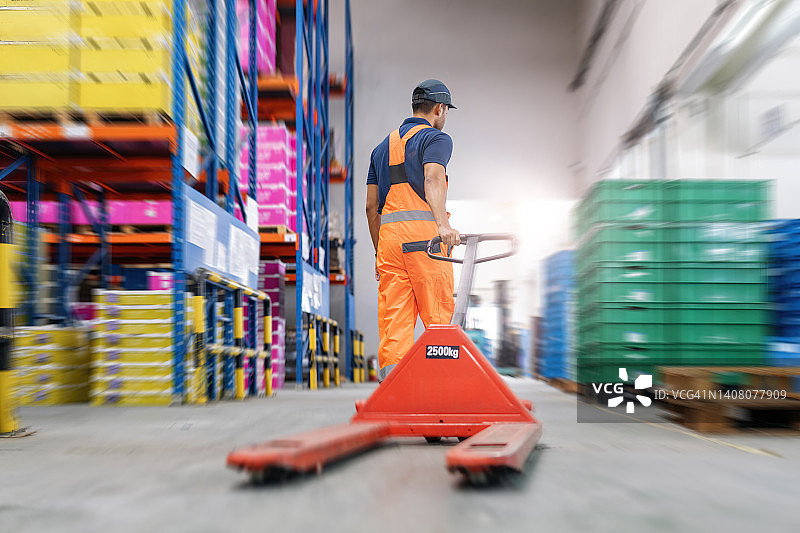 在仓库里拉手动托盘车的工人图片素材