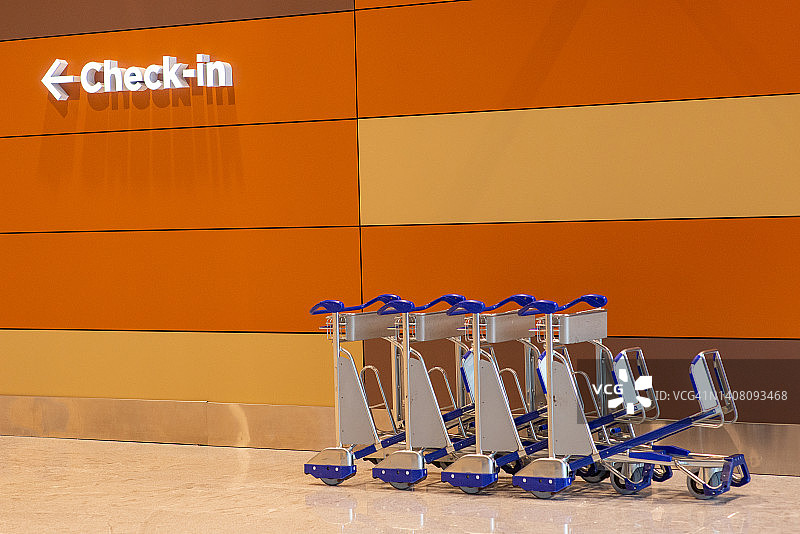 机场入口：指示值机区域的标识与行李车图片素材