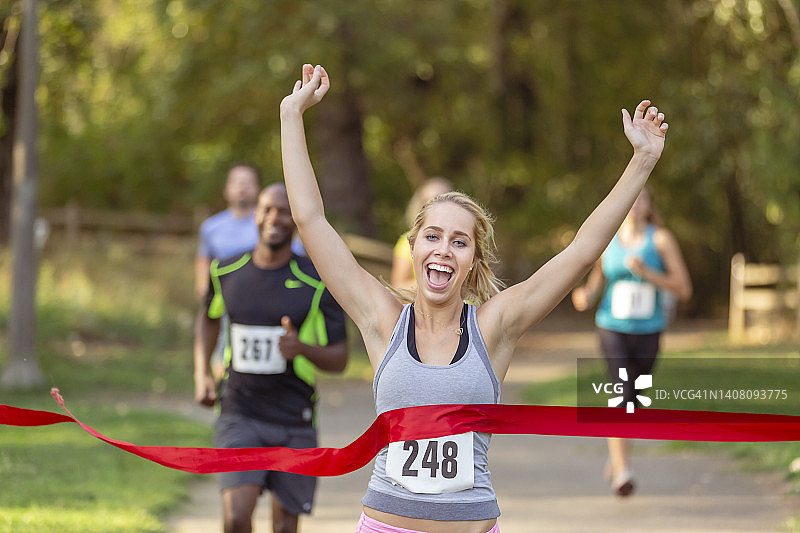 兴奋的女跑步者冲过终点线图片素材