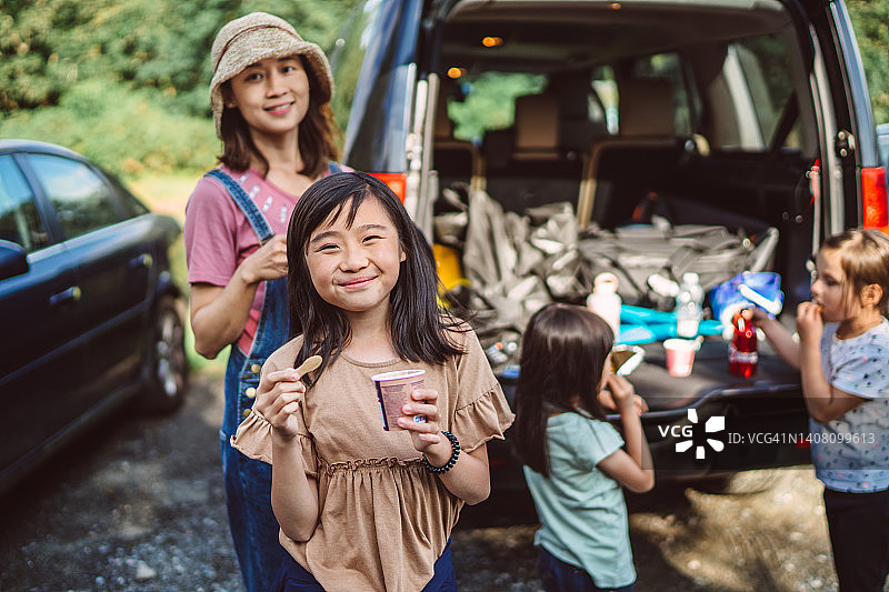 年轻妈妈和快乐的女儿在汽车后备箱享受冰淇淋图片素材