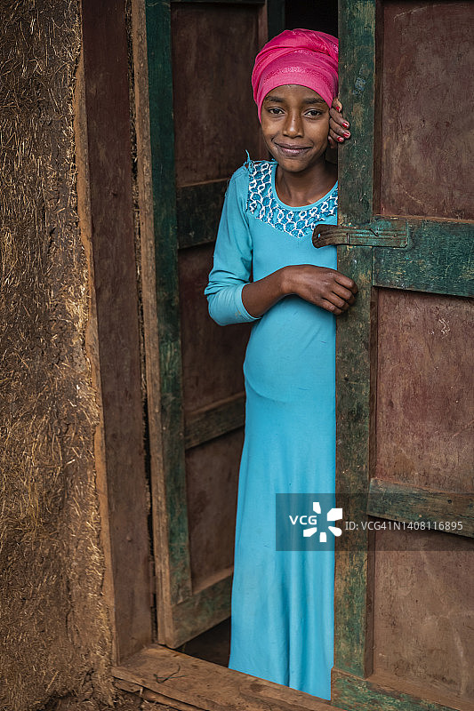 在埃塞俄比亚，非洲裔年轻女孩向屋外看图片素材