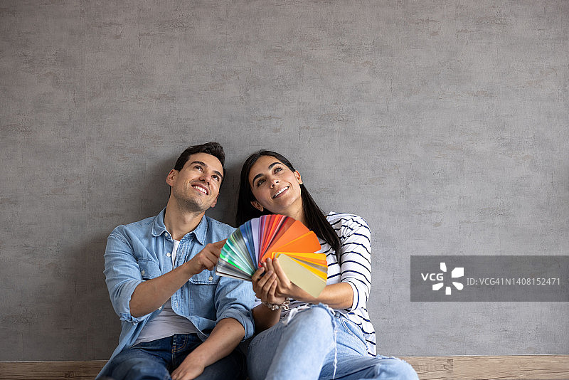 夫妻在家考虑粉刷墙壁，手持色卡图片素材