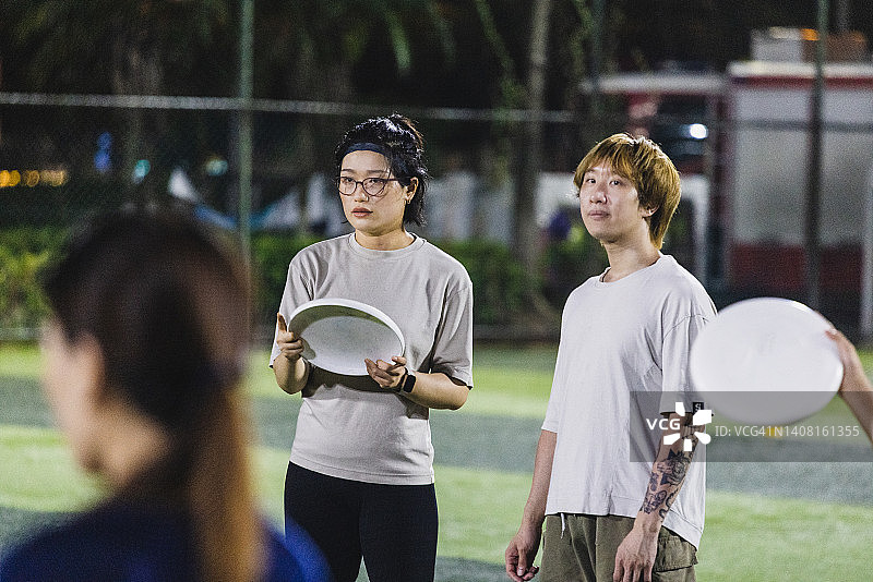 朋友们在足球场玩飞盘图片素材