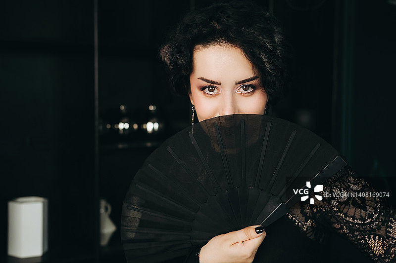 年轻女人手持折扇遮面图片素材