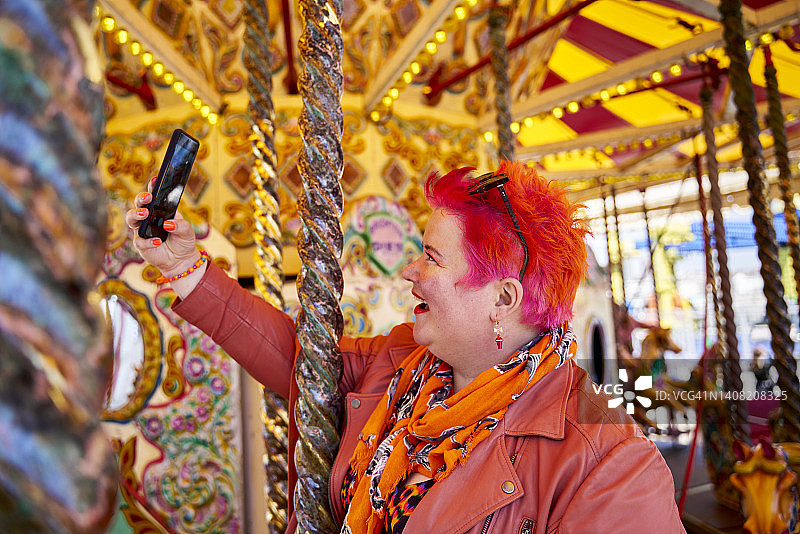 在旋转木马上自拍的红发女人图片素材