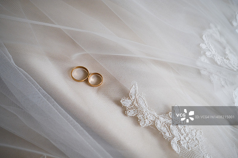 新娘面纱上的金色结婚戒指，精美镂空连衣裙上的珠宝，婚礼，忠诚与爱的象征图片素材