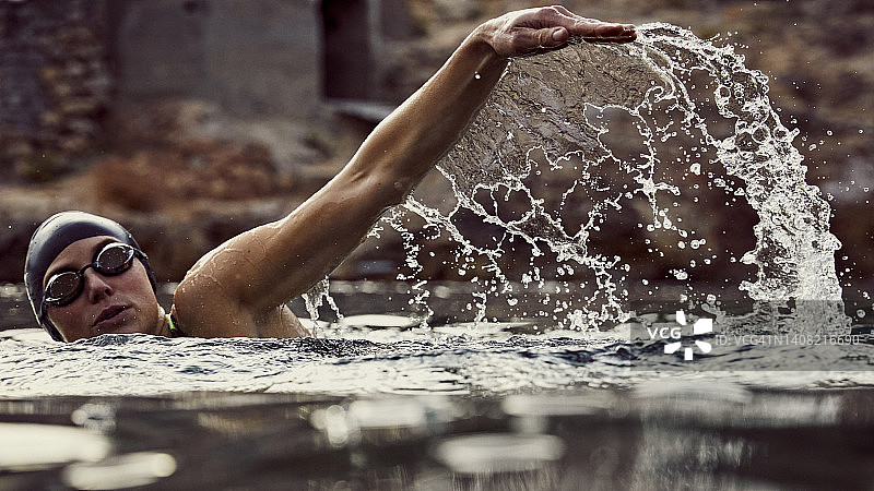 捕捉到的水花飞溅，一位女性游泳者正在享受日落时分的海泳图片素材