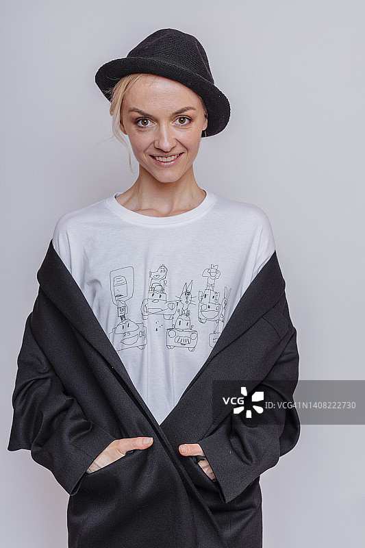 戴着猪肉馅饼帽，在灰色背景的工作室里摆姿势的微笑女性图片素材