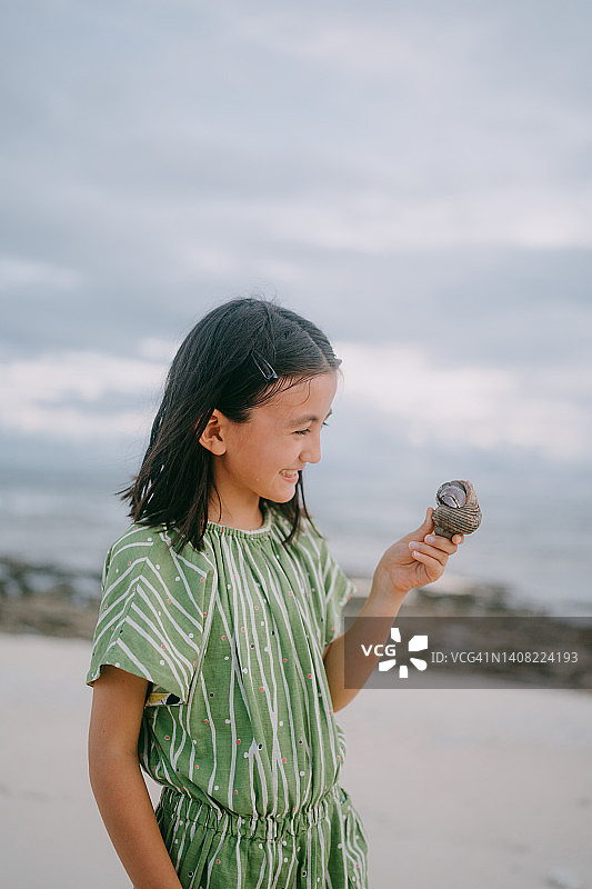 在日本海滩上拿着巨型寄居蟹的年轻女孩图片素材