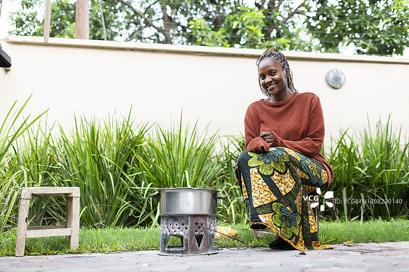 坐在户外烹饪火盆旁的传统服饰年轻女子图片素材