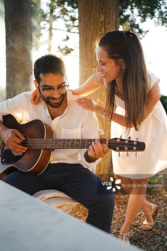 男人在日落时演奏原声吉他，女人相伴图片素材