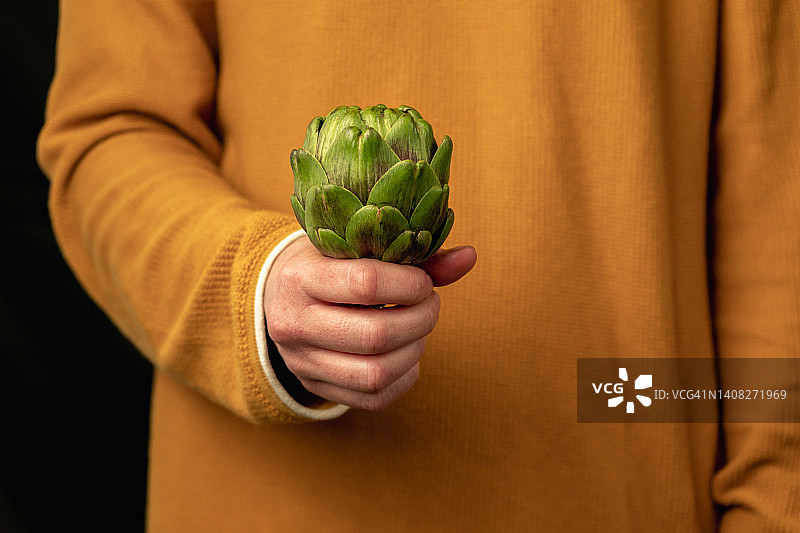 女人手拿新鲜绿色洋蓟图片素材
