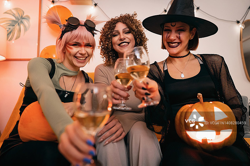 三个万圣节装扮的年轻白人女性一起喝酒玩乐图片素材