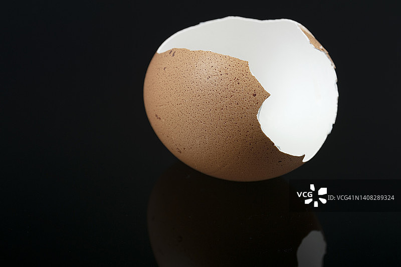 黑色背景上的破碎鸡蛋壳特写图片素材