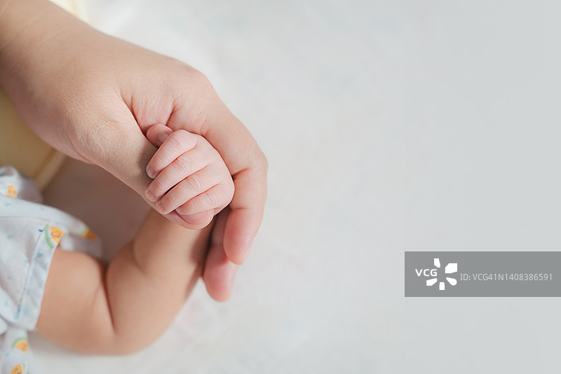 亚洲父母手握新生婴儿手指特写图片素材