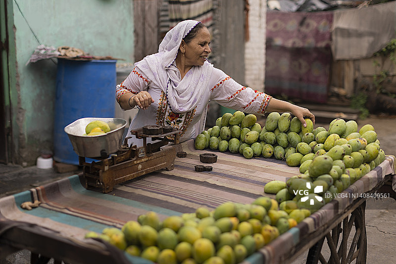 中年妇女在路边卖芒果图片素材
