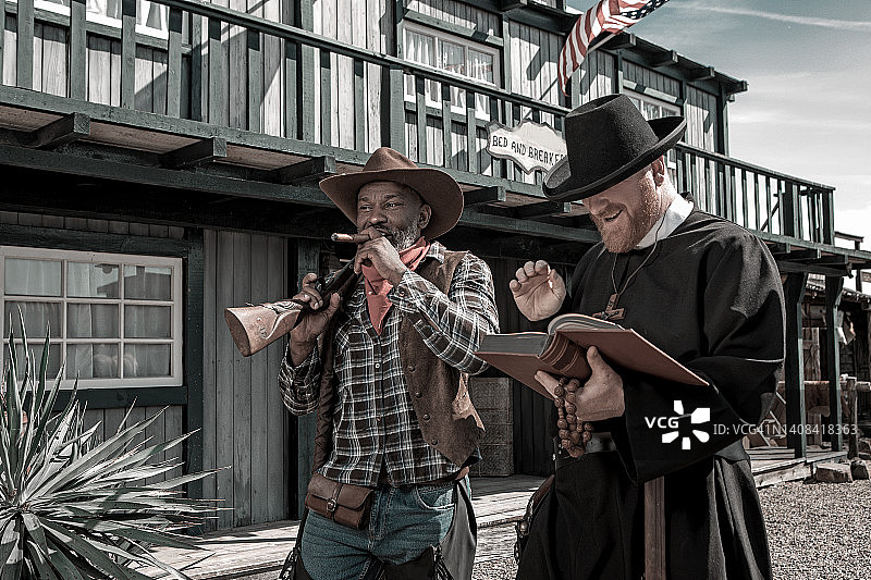 帅气黑人牛仔与牧师在狂野西部背景中图片素材