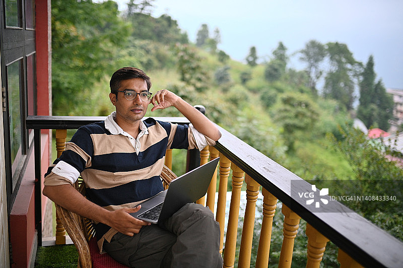 男人在风景优美的偏远阳台上用笔记本电脑工作图片素材