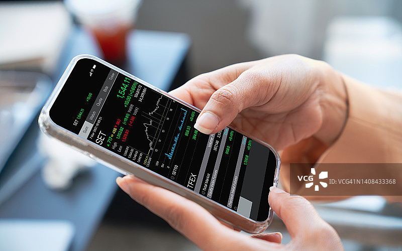 女人在咖啡店使用智能手机查看股票市场图表图片素材