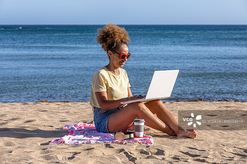 西班牙裔女人在海滩上用笔记本电脑浏览网页图片素材