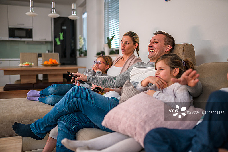 温馨的白人家庭坐在沙发上换频道图片素材