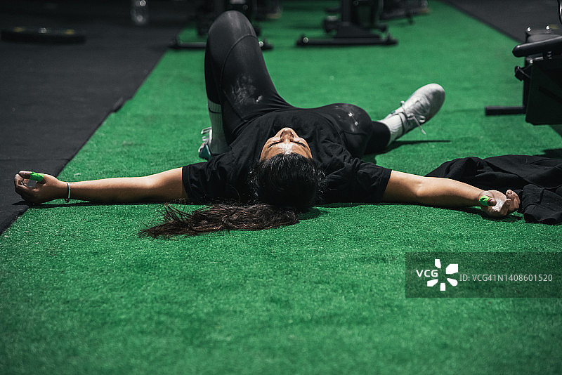 训练后躺在地板上的疲惫年轻女人图片素材