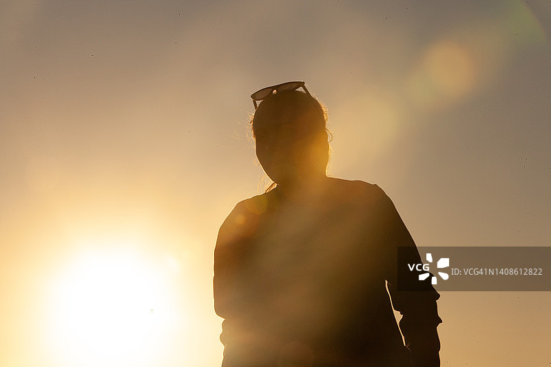 戴着太阳镜的少女剪影：阳光照射图片素材