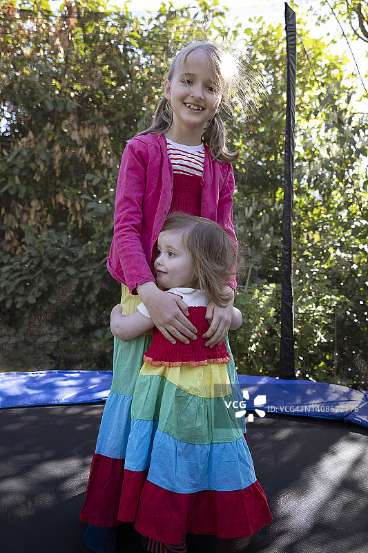 幼儿在蹦床上拥抱开心的哥哥图片素材