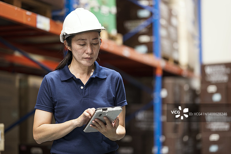 亚洲女性仓库经理在仓库使用平板盘点库存图片素材
