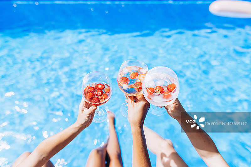 在阳光明媚的炎热天气里，女士在泳池边享受饮品图片素材