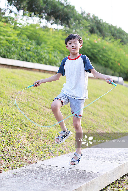 小男孩在草地上跳绳图片素材