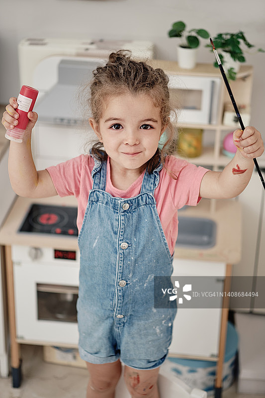 手里拿着刷子和颜料管的快乐女孩图片素材