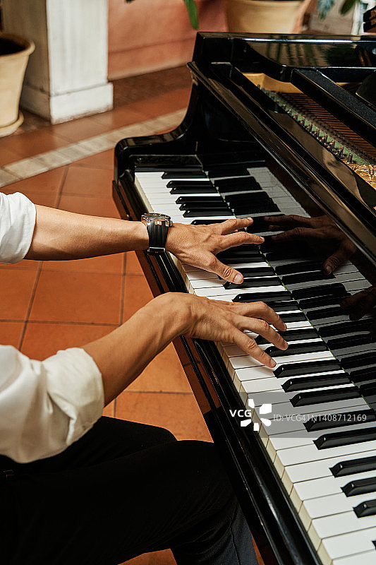 一位优雅的钢琴家弹奏三角钢琴的手部特写图片素材