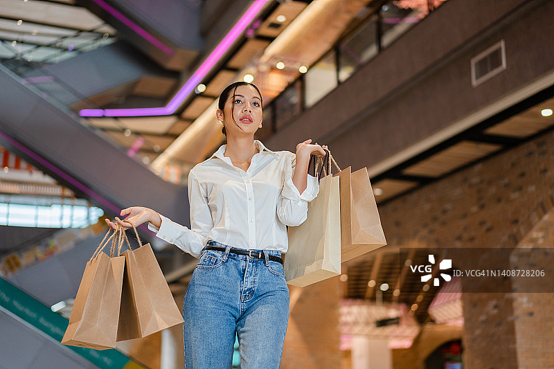 快乐的亚洲年轻女人在城市购物中心购物图片素材