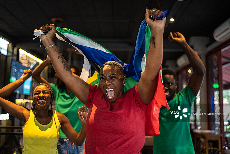 在酒吧观看比赛并庆祝的体育迷朋友图片素材